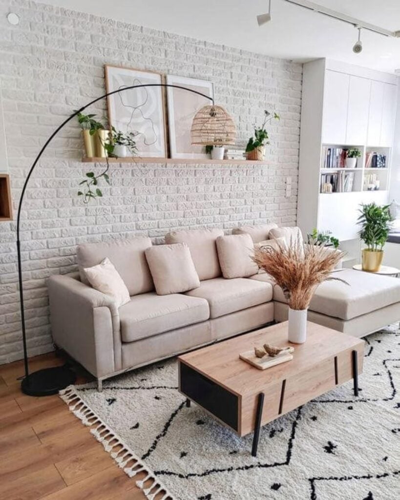 Sala de estar com sofá rosa-claro, parede de tijolinhos e luminária de piso
