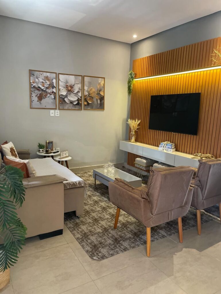 Sala de estar com tapete grande, quadros na parede e painel ripado atrás da tv
