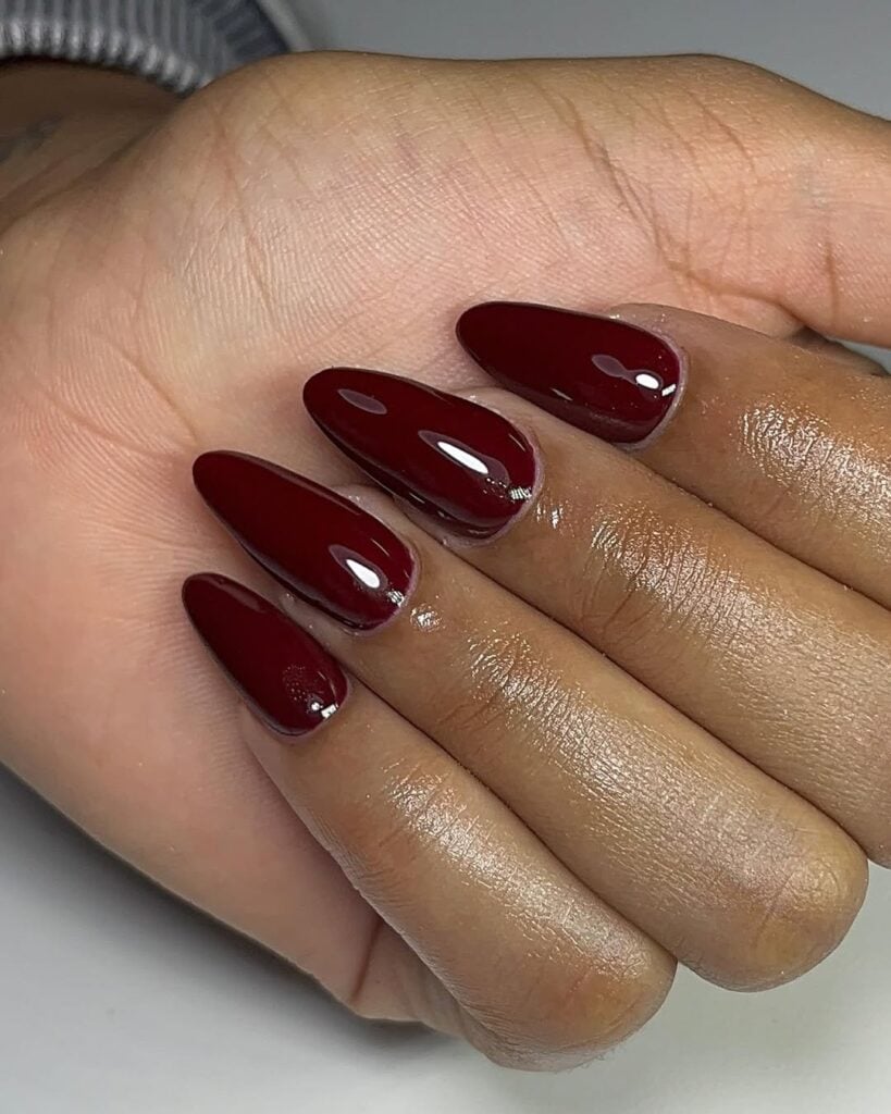 Mão de pele preta, com unha amendoada burgundy