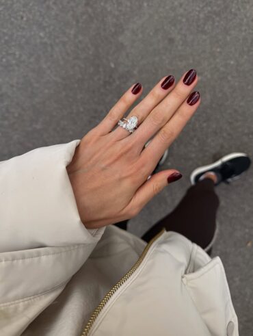 Mão de pele clara, com anéis de brilhante e unha redonda burgundy