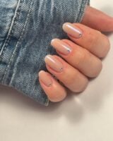 Mão de pele clara, com unha neutra perolada e strass