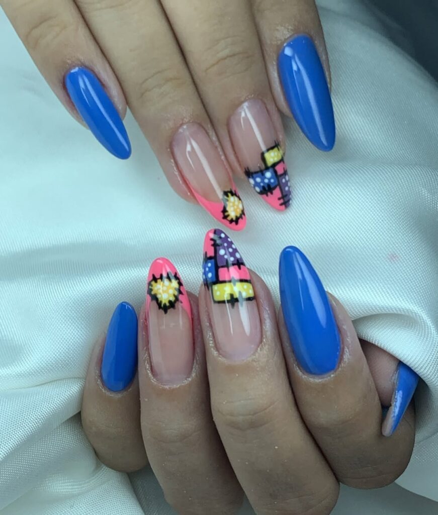 Mãos de pele clara, com unha amendoada azul com inglesinha rosa e decoração com retalhos coloridos