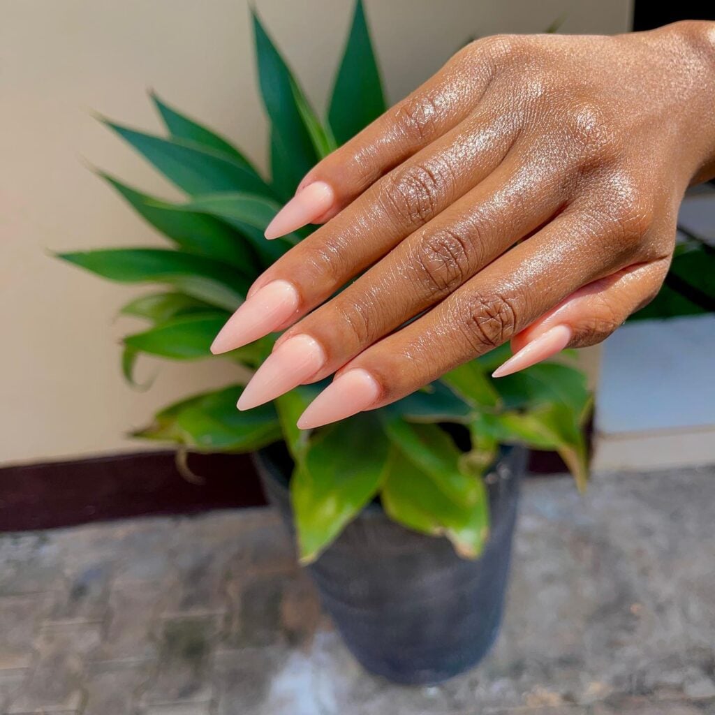 Mão de pele preta, com unha amendoada pintada com esmalte nude rosado