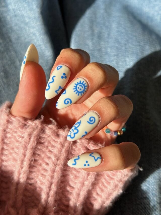 Mão de pele clara, com unha neutra amendoada com decoração em azul