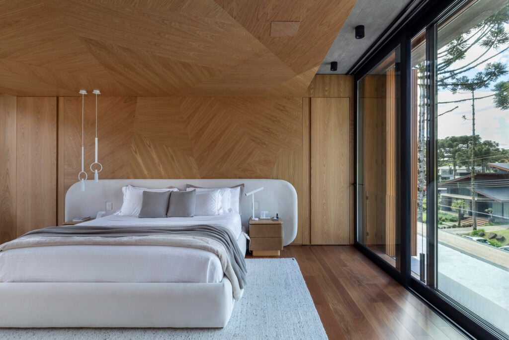 Quarto de casal com cabeceira arredondada e parede de madeira