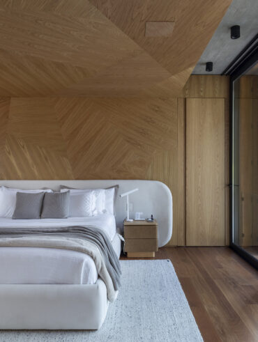 Quarto de casal com cabeceira arredondada e parede de madeira