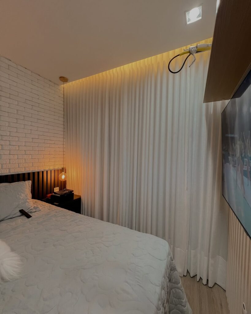 Quarto com parede de tijolinhos branca e cortina blackout na mesma cor