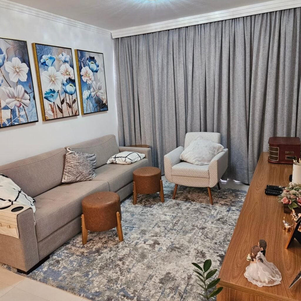 Sala de estar sofá cinza, pufes em couro marrom e cortina cinza