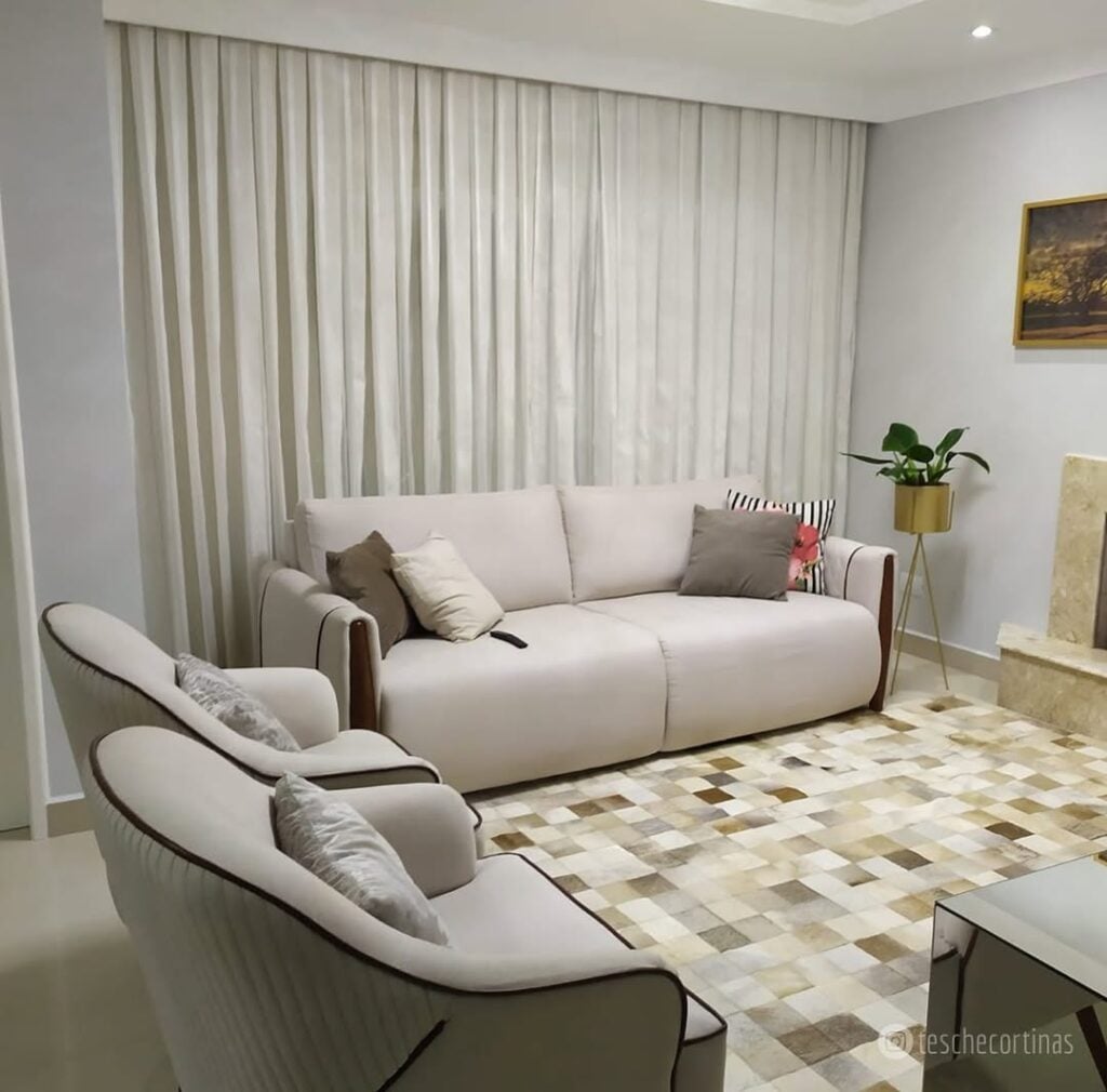 Sala de estar sofá branco, tapete quadriculado e cortina branca