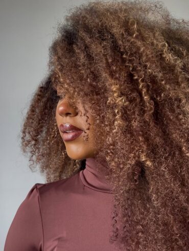 Mulher de pele preta, com blusa marrom avermelhada e cabelo crespo