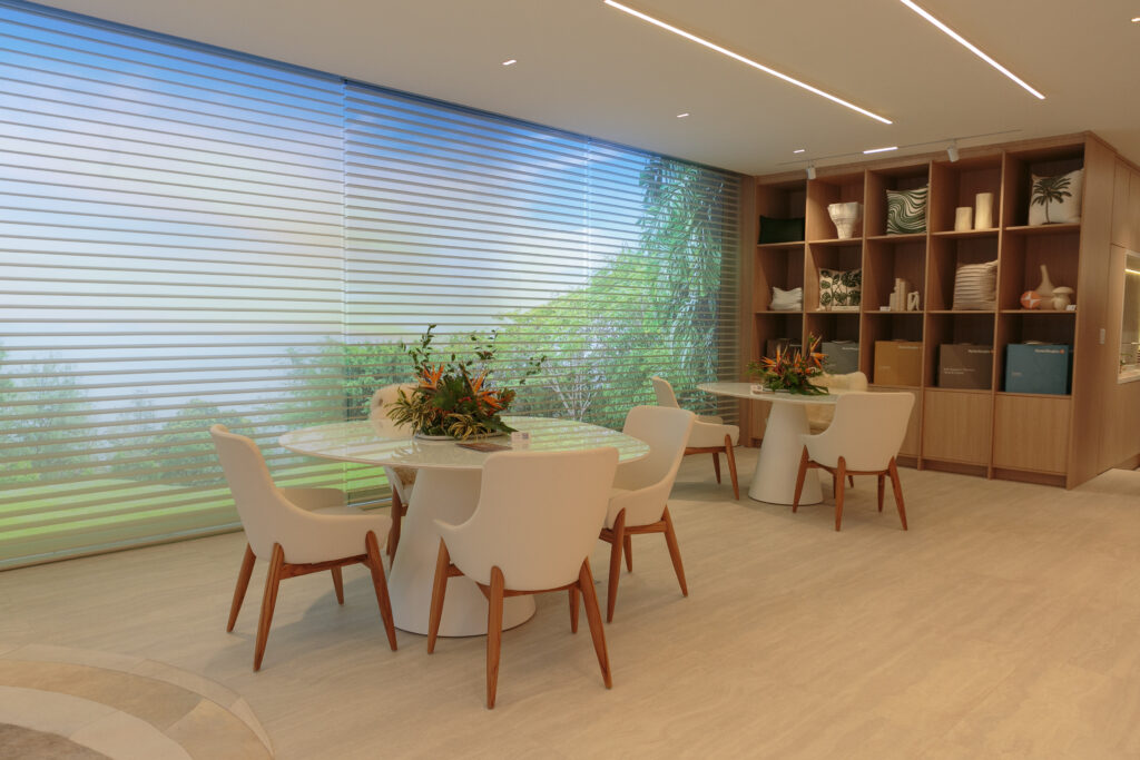 Sala com mesas e cadeiras brancas e estante em madeira