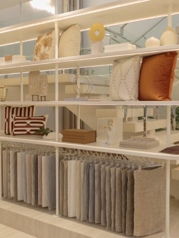 Estante branca com almofadas e amostras de tecidos de cortinas