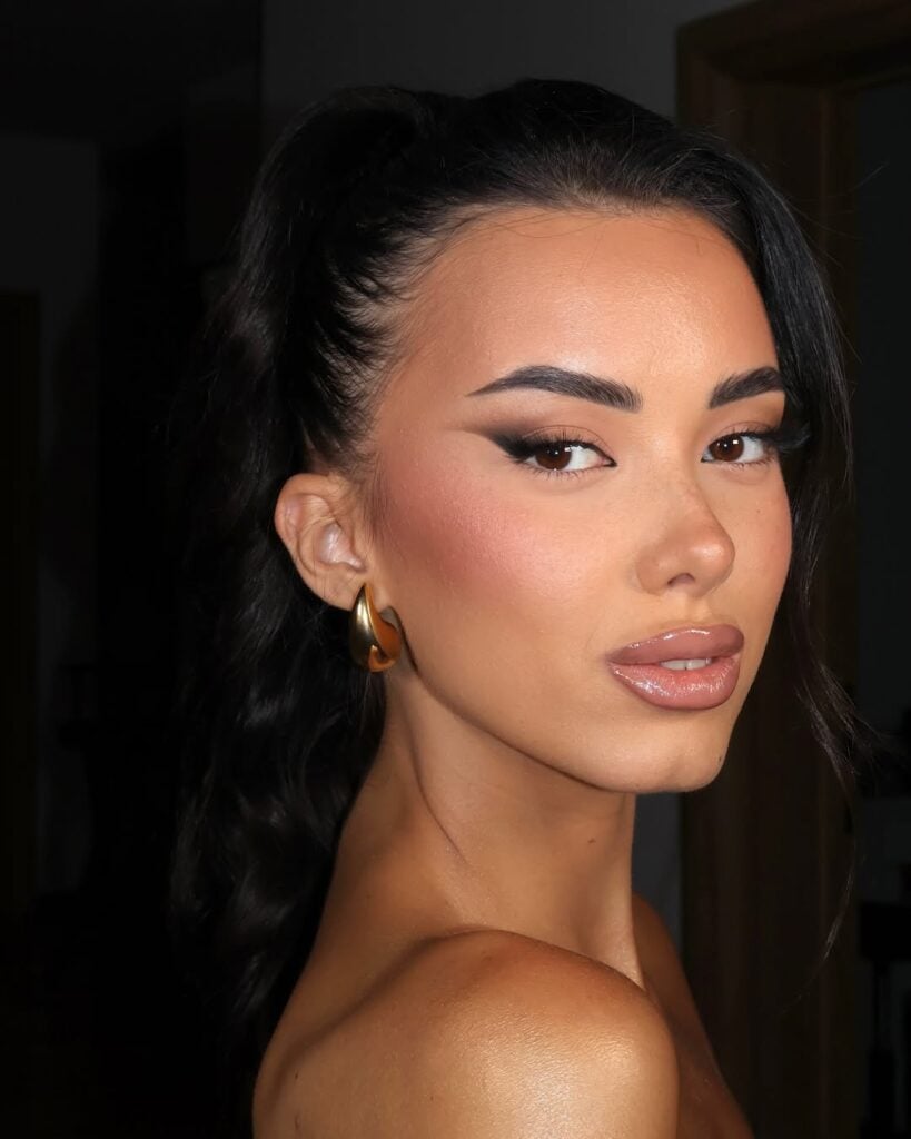 Mulher de pele clara, com cabelo escuro preto e maquiagem com delineado esfumado 