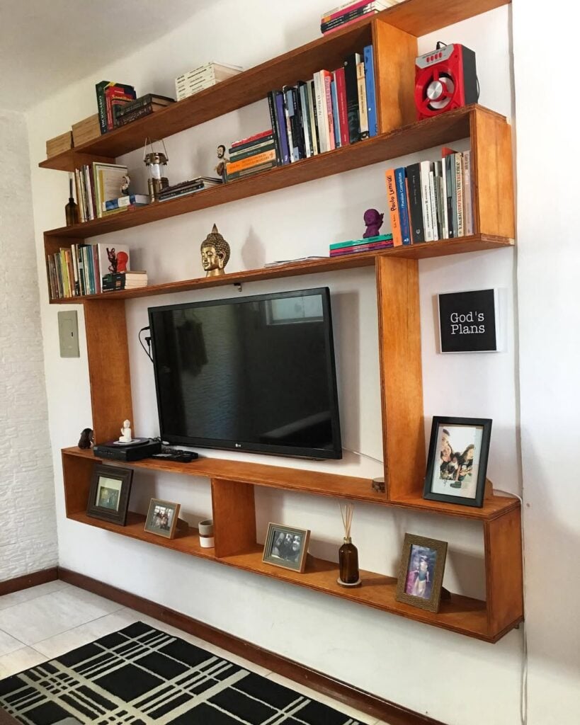 Estante de madeira suspensa com livros e tv