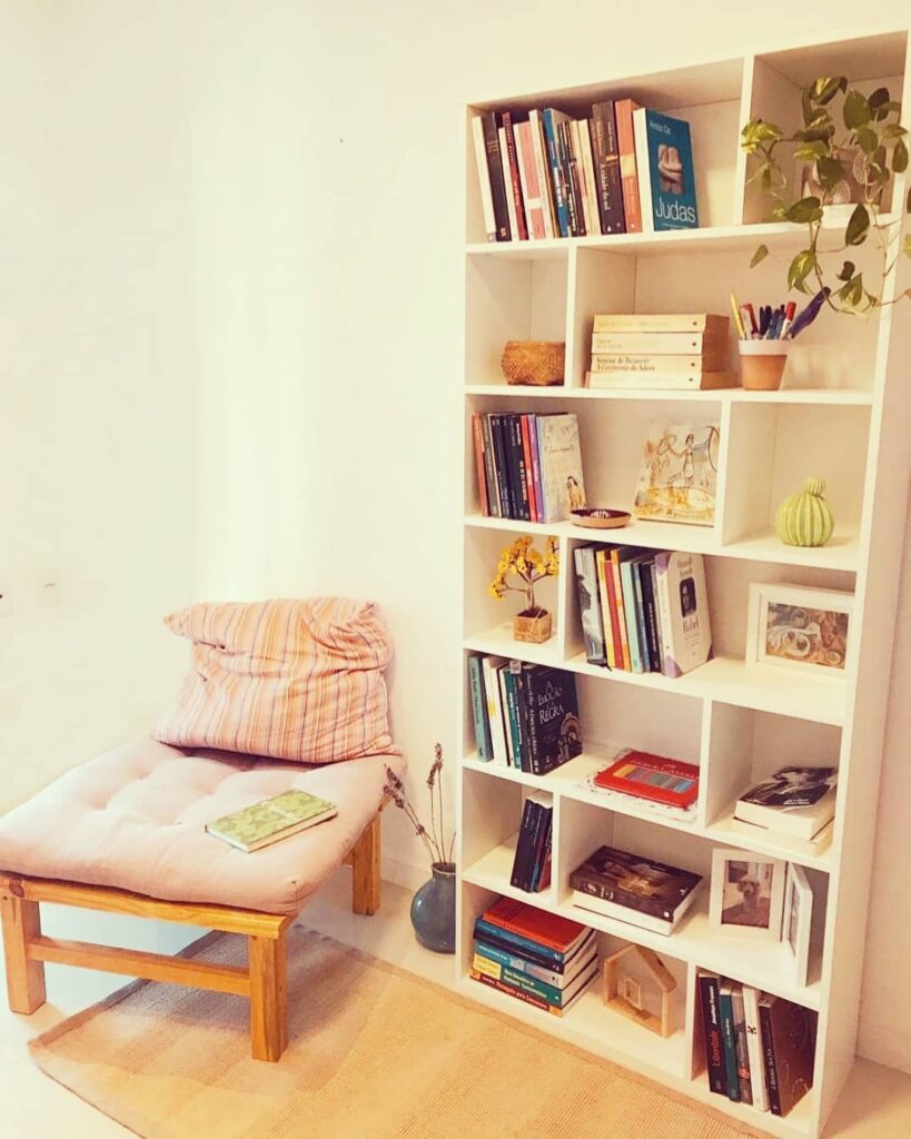Canto da leitura com estante branca com nichos e objetos decorativos