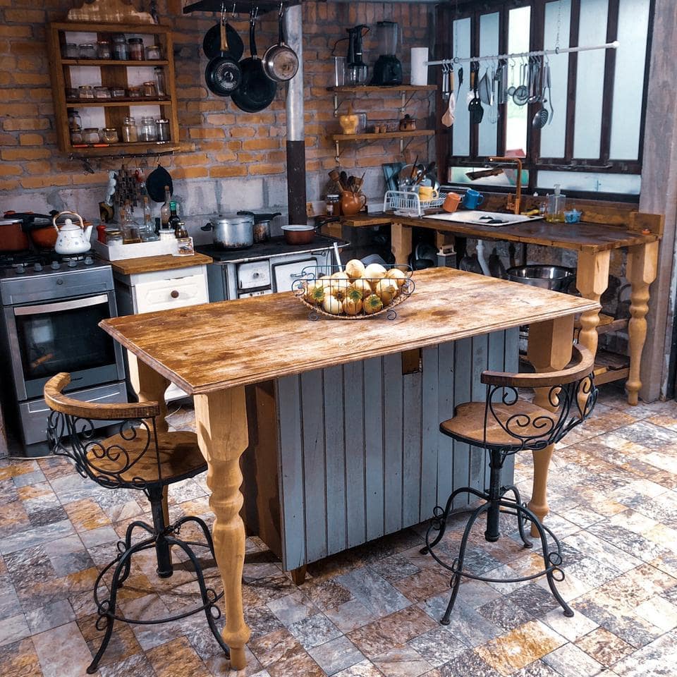 Inspiração de cozinha rústica com tijolo aparente, ilha e prateleiras