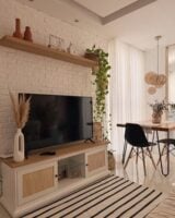 Sala de estar aconchegante com TV, rack, tapete e cortina branca