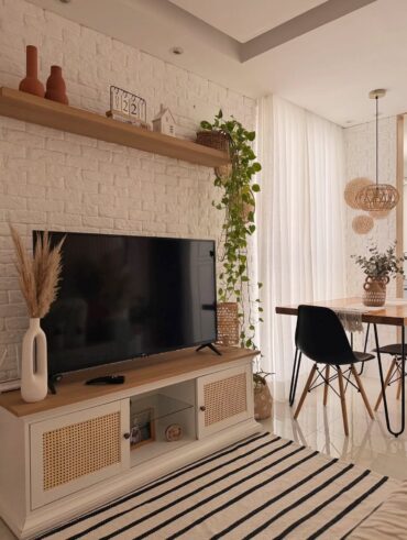 Sala de estar aconchegante com TV, rack, tapete e cortina branca