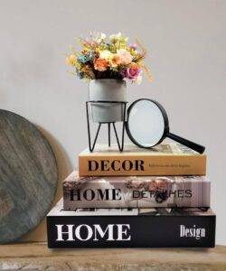 Decoração com caixas de livros, vasinho de flores e lupa