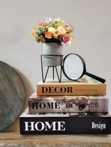 Decoração com caixas de livros, vasinho de flores e lupa