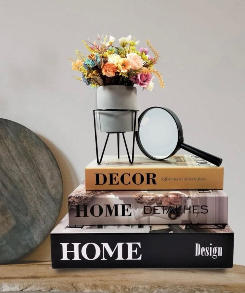 Decoração com caixas de livros, vasinho de flores e lupa