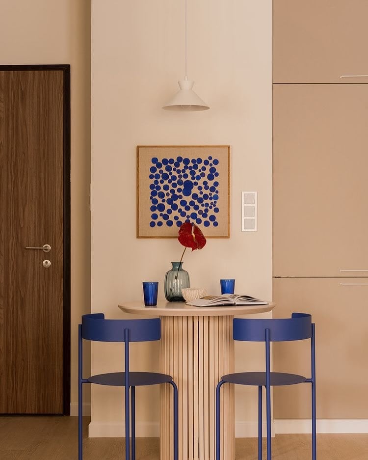 Espaço com mesa em tom claro e cadeiras de metal azuis