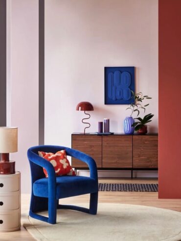 Sala de estar com poltrona na cor Luminous Blue com almofada em vermelho e branco