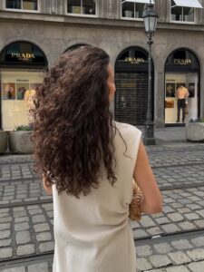 Mulher de pele clara, com blusa branca e cabelo cacheado