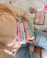 Mulher de pele clara, segurando os livros da série Chestnut Springs