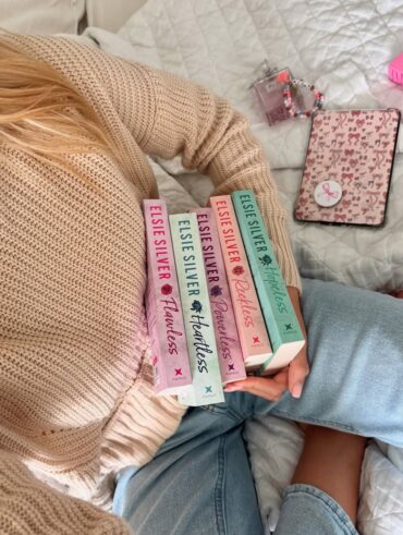 Mulher de pele clara, segurando os livros da série Chestnut Springs
