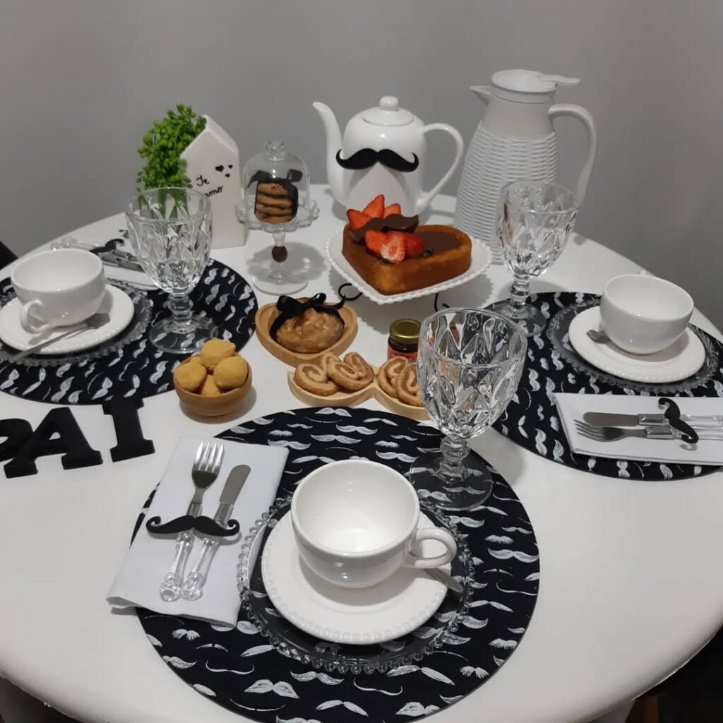 Mesa redonda com louças brancas e sousplats pretos com bigodinhos