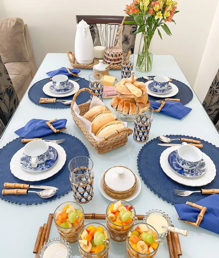 Mesa posta de café da manhã com sousplats azuis, louças em branco e azul