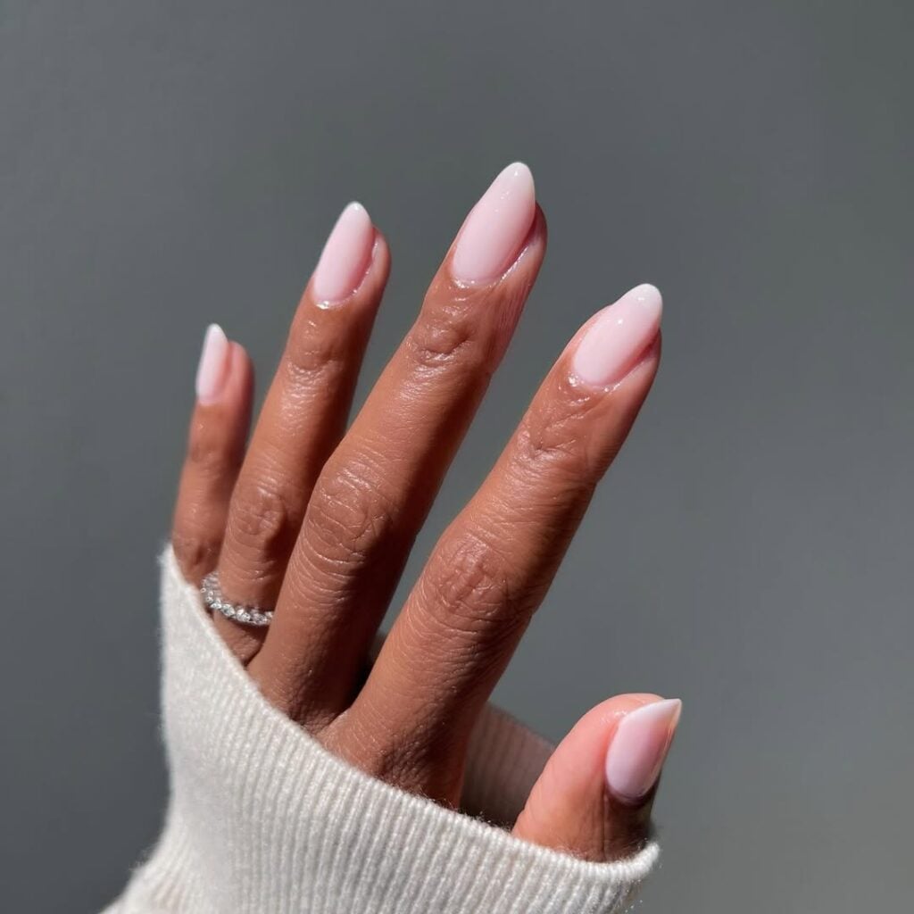 Mão de pele preta, com anel de brilhante e unha amendoada milky nail 