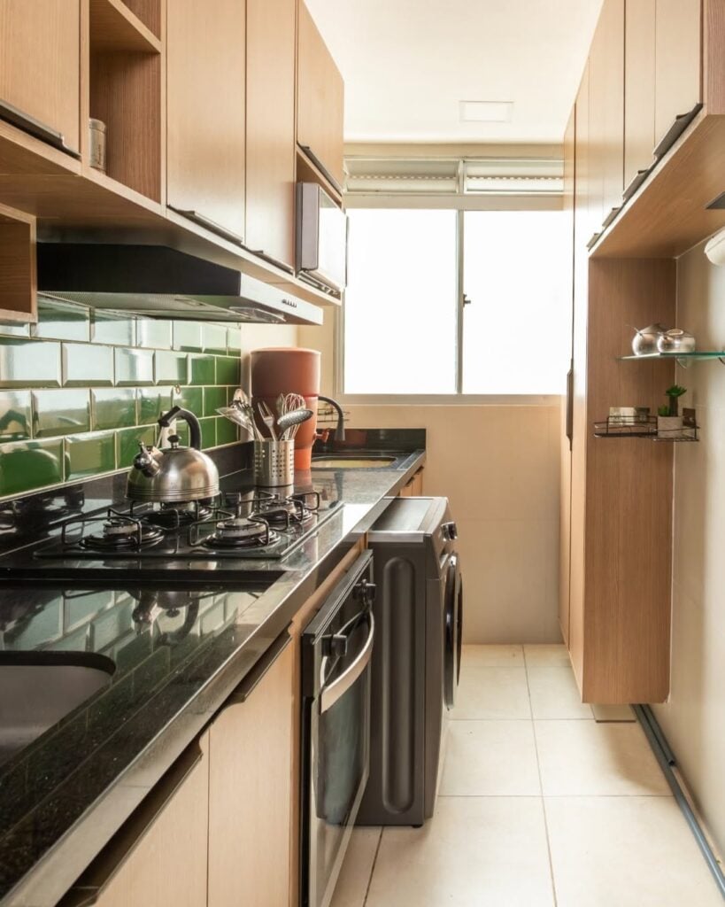 Cozinha em linha reta com armários claros e revestimento verde