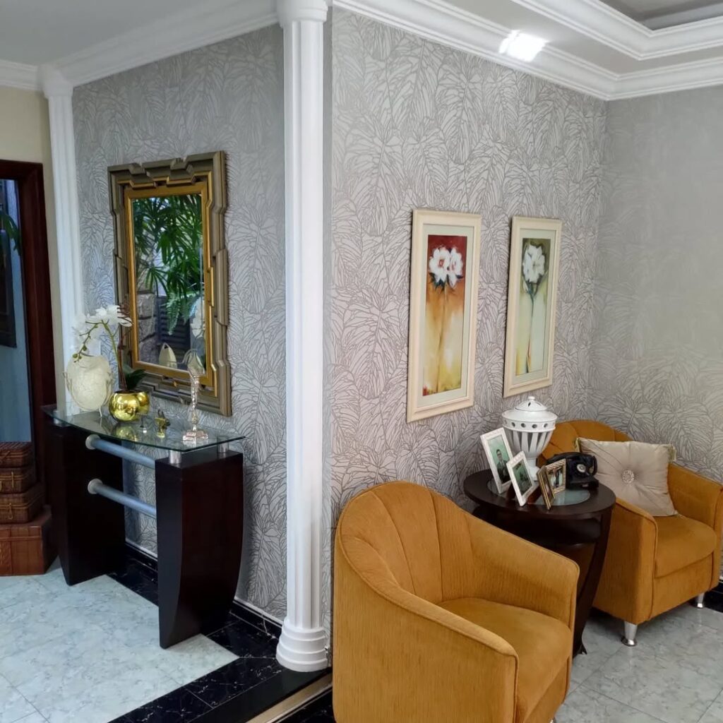 Sala de estar com papel de parede em tons de cinca e poltronas caramelo
