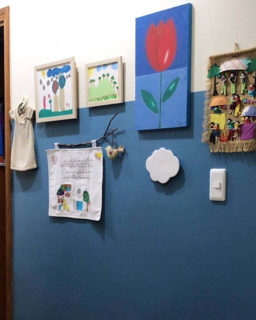 Parede azul e branca com quadros e desenhos