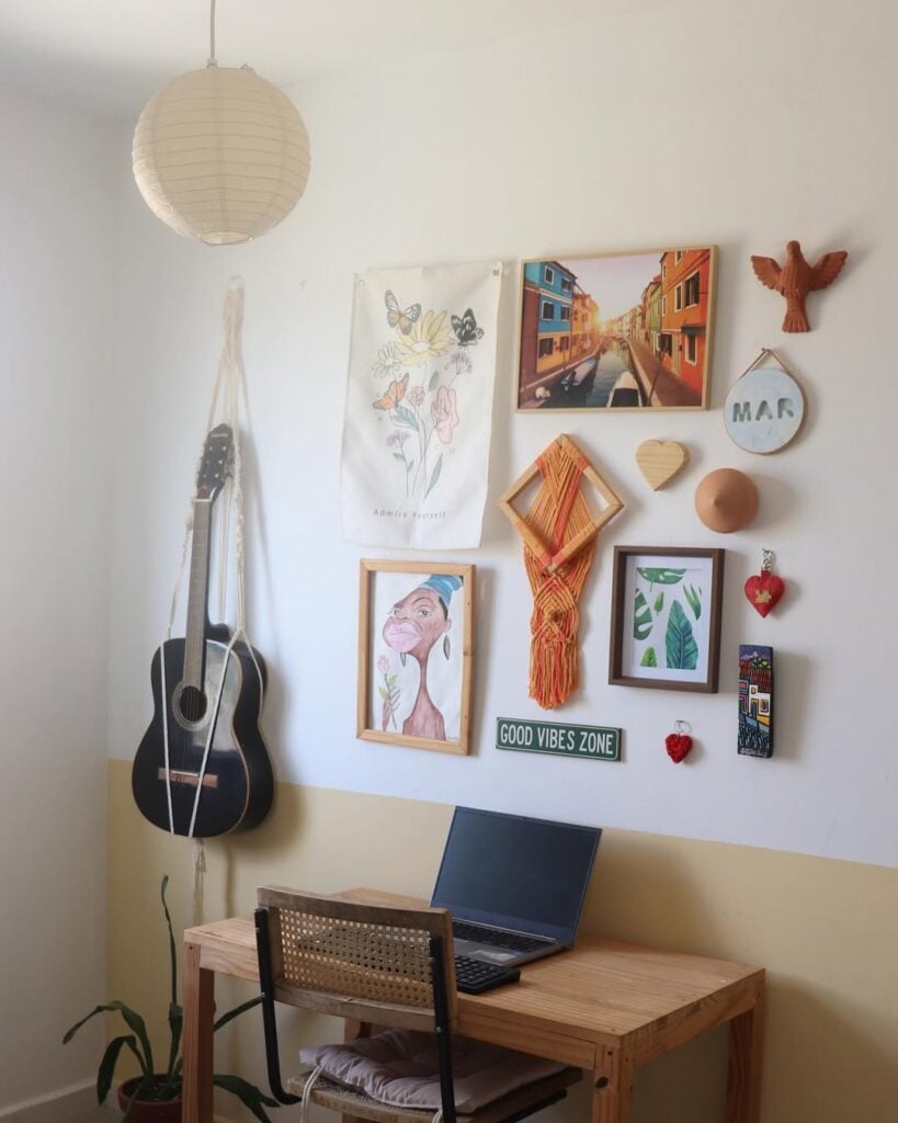 Parede branca com violão pendurado, quadros e enfeites