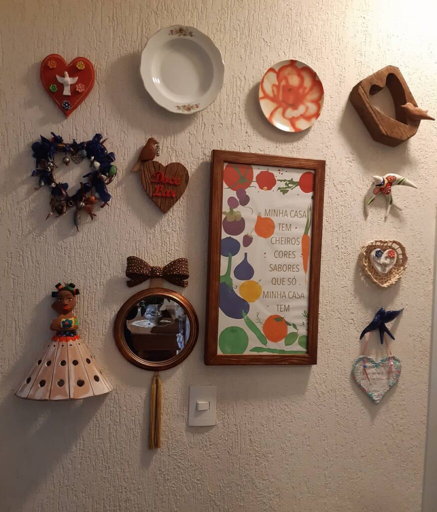 Parede enfeitada com pratos, quadro e objetos em formato de coração