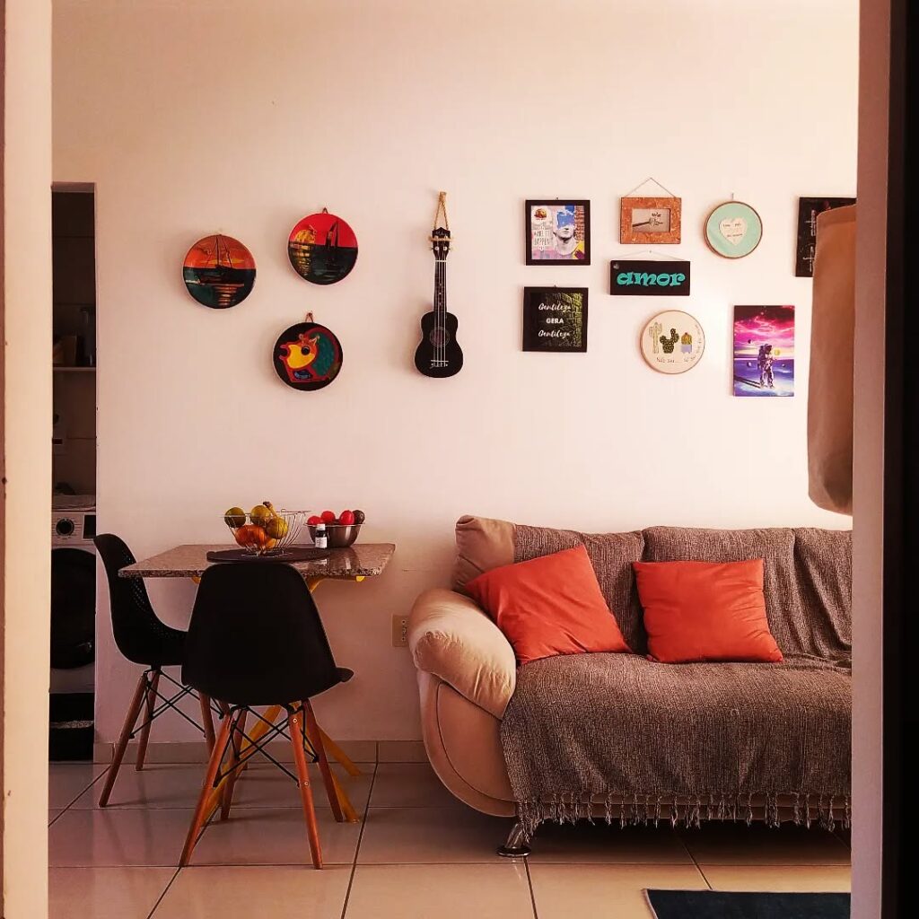 Sala de estar com sofá, mesinha e parede com pratos e quadrinhos coloridos
