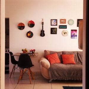 Sala de estar com sofá, mesinha e parede com pratos e quadrinhos coloridos