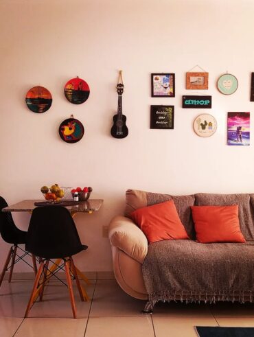 Sala de estar com sofá, mesinha e parede com pratos e quadrinhos coloridos