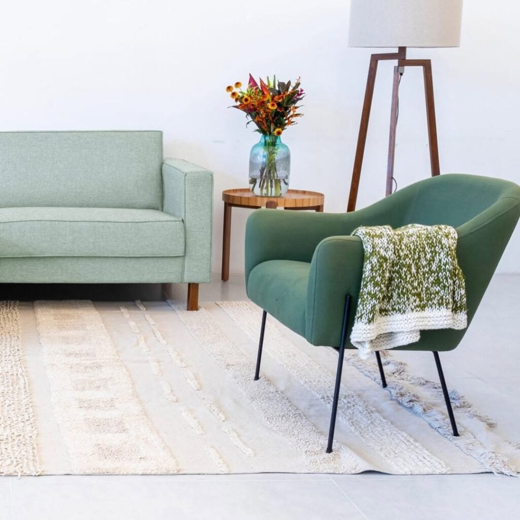 Sala de estar com poltrona verde e pés de metal preto