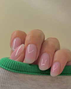Mão de pele clara, com unha amendoada rosa translúcido