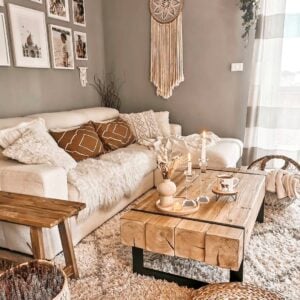 Sala de estar boho om sofá claro, almofadas e mantas, mesa de centro de madeira com metal
