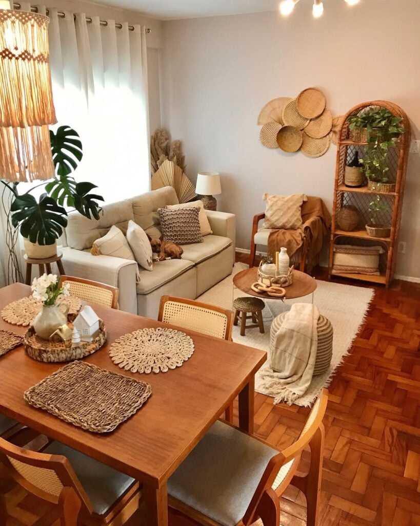 Sala de estar e jantar integradas, com sofá cinza-claro, tapete, estante em vime e objetos em fibras naturais
