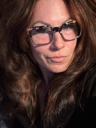 Mulher de 50 anos com pele madura, cabelo longo castanho e óculos de grau
