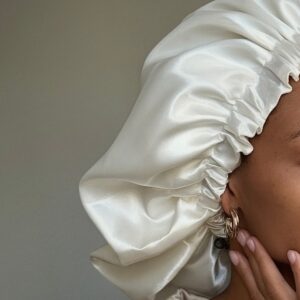 Mulher de pele preta, com acessórios em dourado e touca de cetim