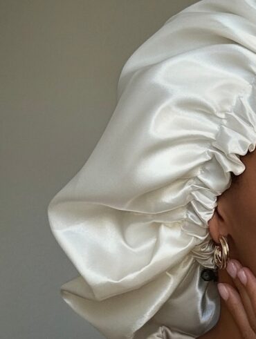 Mulher de pele preta, com acessórios em dourado e touca de cetim