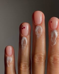 Mão de pele clara, com unha curta neutra com cerejas