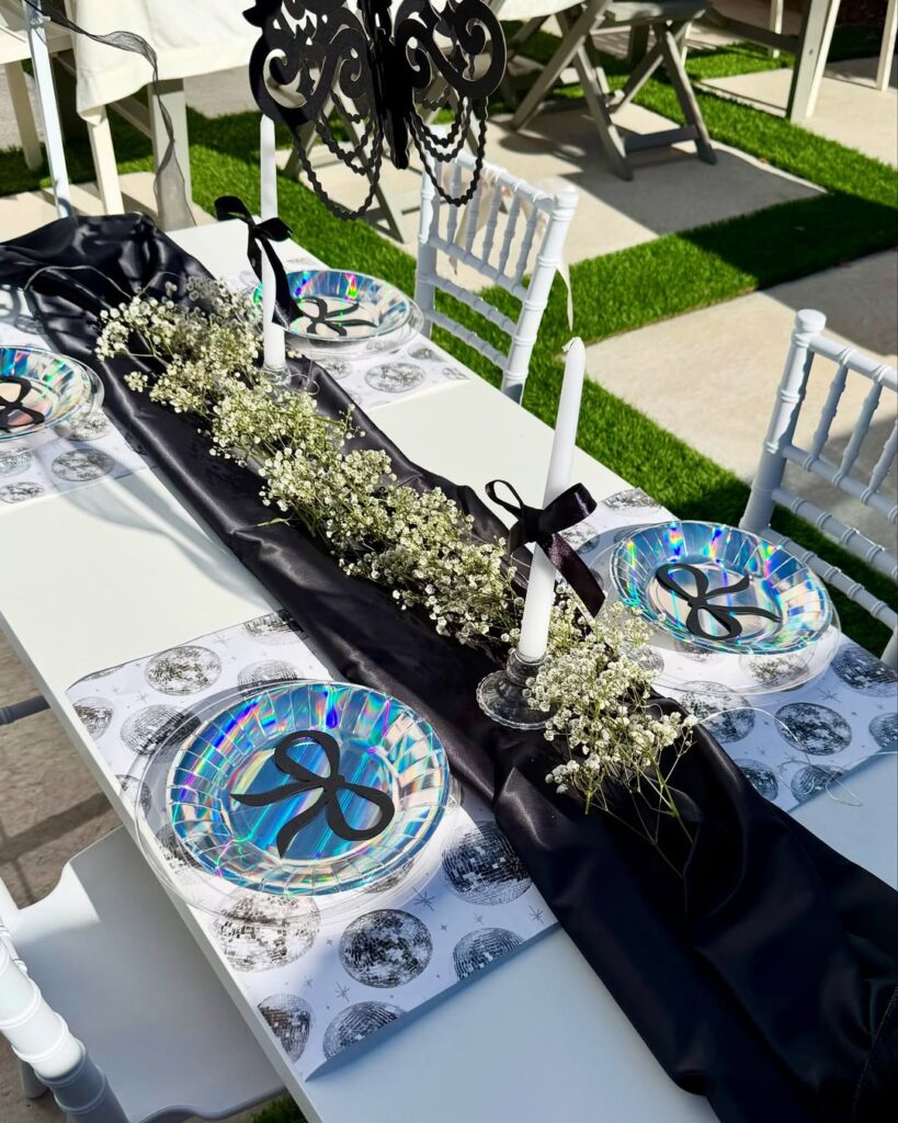 mesa com pratos com desenho de laço, guardanapo e velas